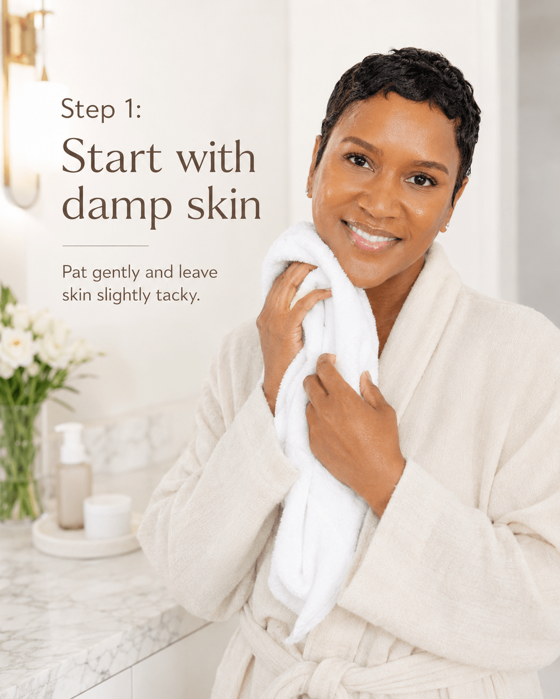 Black woman in a cream robe gently patting her face dry with a white towel in a marble bathroom, with text reading "Step 1: Start with damp skin."
